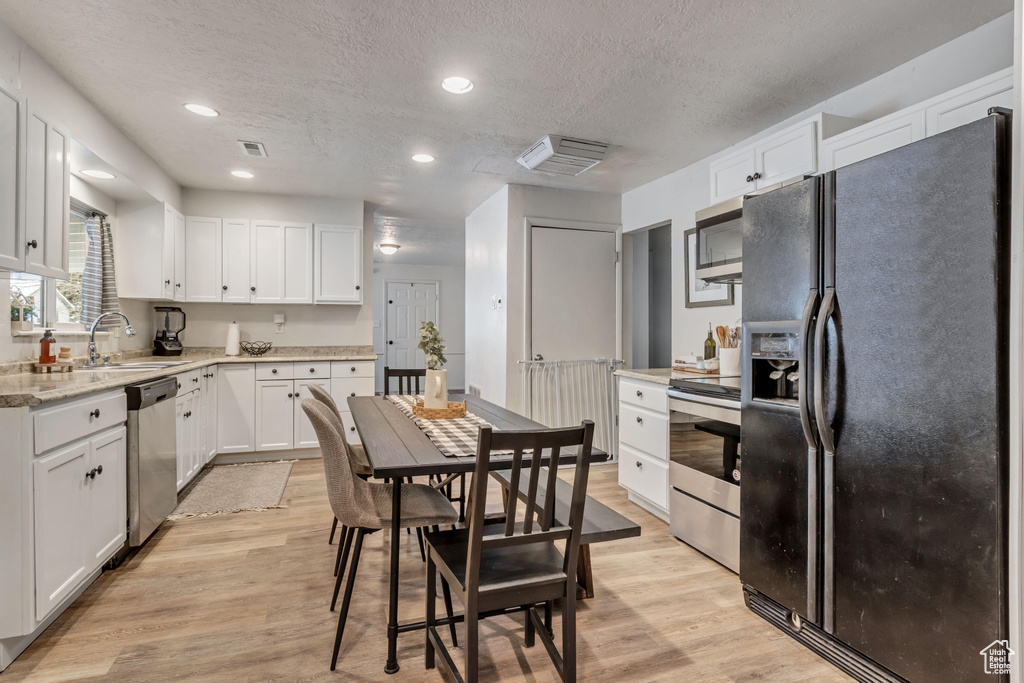 Kitchen featuring light hardwood / wood-style floors, a textured ceiling, stainless steel appliances, sink, and white cabinetry