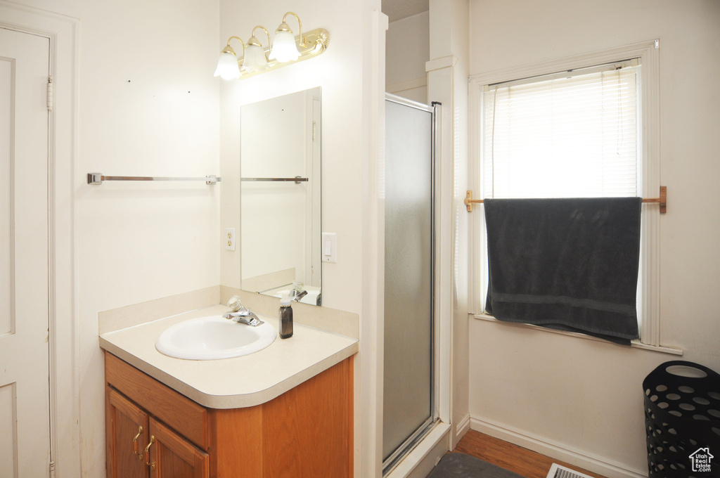 Bathroom featuring hardwood / wood-style floors, vanity, and an enclosed shower