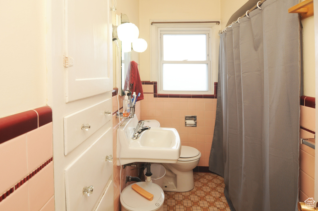 Bathroom featuring tile floors, sink, tile walls, and toilet