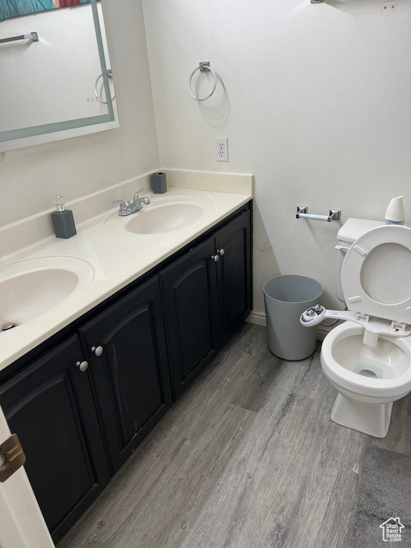 Bathroom featuring toilet, dual bowl vanity, and hardwood / wood-style floors