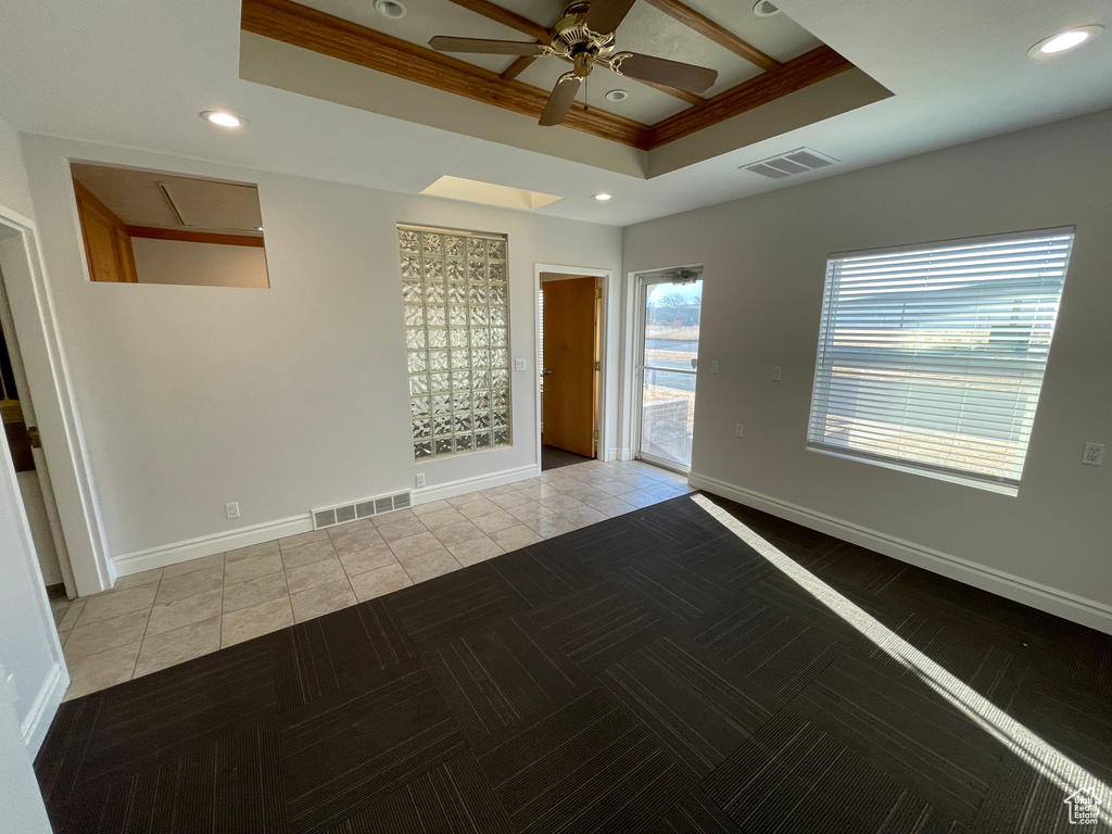 Tiled empty room featuring a raised ceiling and ceiling fan