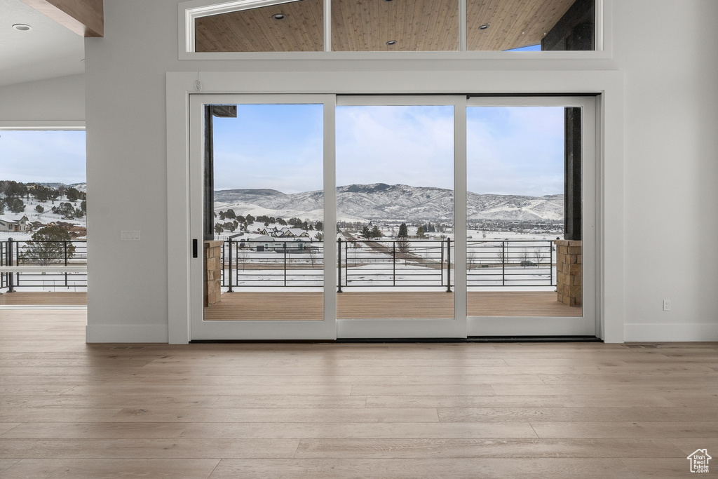 Doorway to outside featuring a mountain view, lofted ceiling, light hardwood / wood-style floors, and wood ceiling