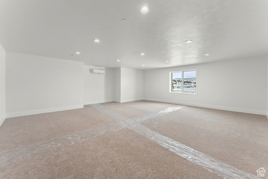 Unfurnished room featuring light colored carpet and an AC wall unit