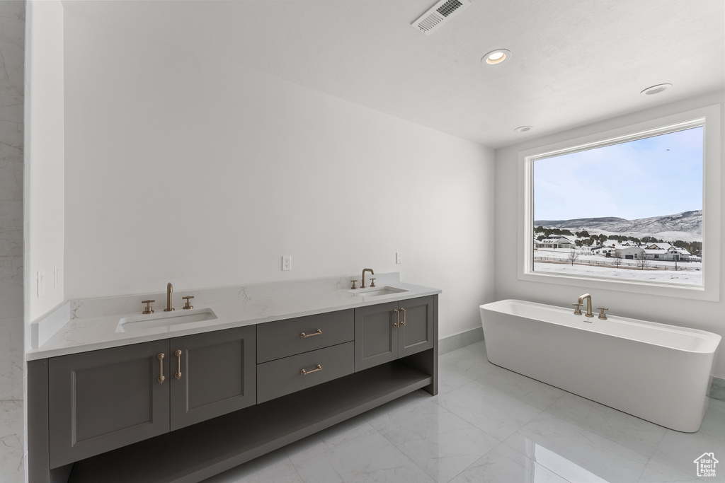 Bathroom with dual vanity, tile flooring, and a washtub