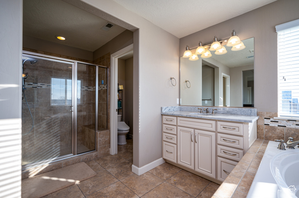 Full bathroom featuring independent shower and bath, toilet, vanity with extensive cabinet space, and tile flooring