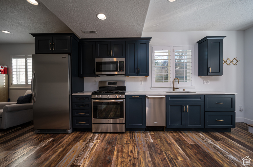 Kitchen with dark hardwood / wood-style flooring, sink, a textured ceiling, and stainless steel appliances