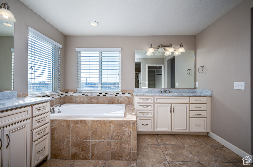 Bathroom featuring tile floors, tiled tub, and vanity