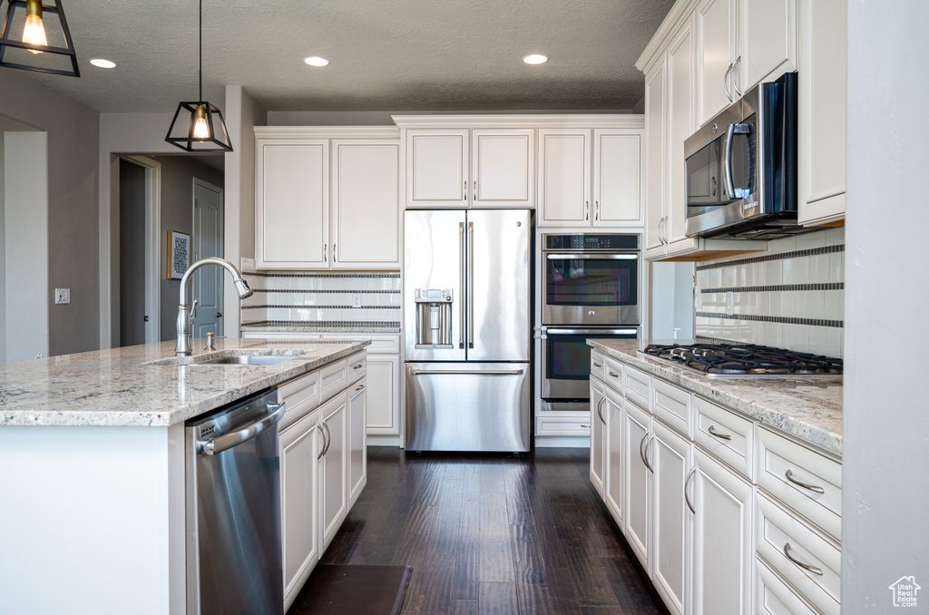 Kitchen featuring white cabinets, hanging light fixtures, sink, and stainless steel appliances