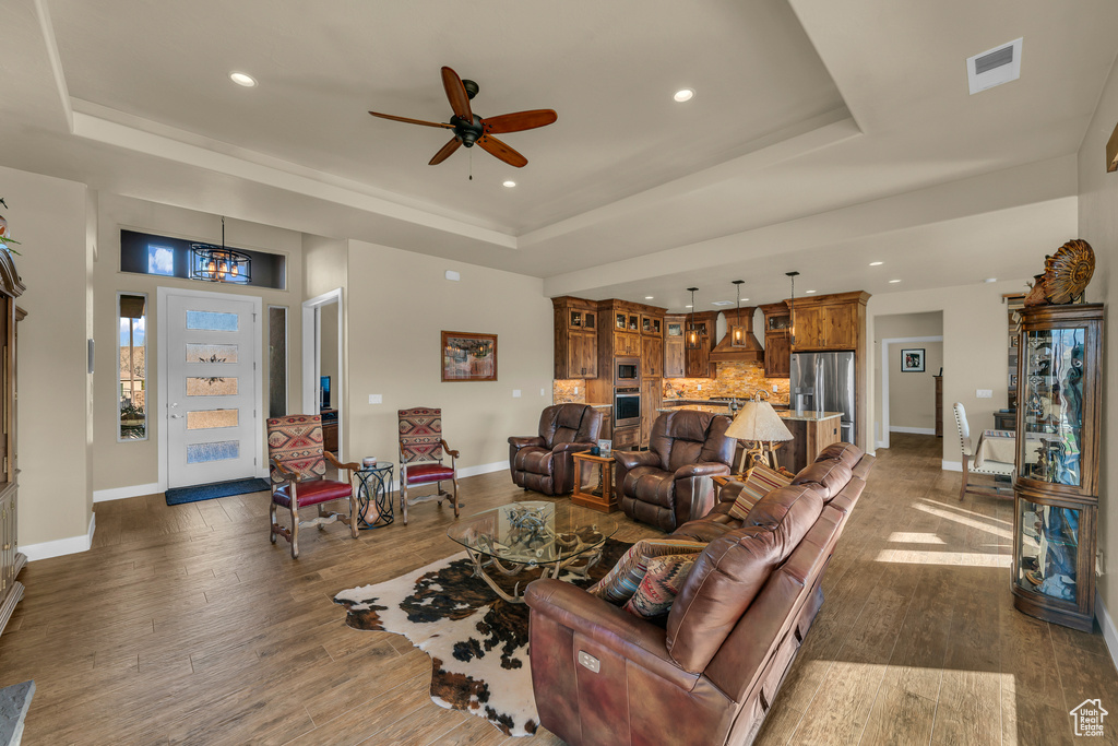 Living room featuring a tray ceiling, dark wood-type flooring, and ceiling fan