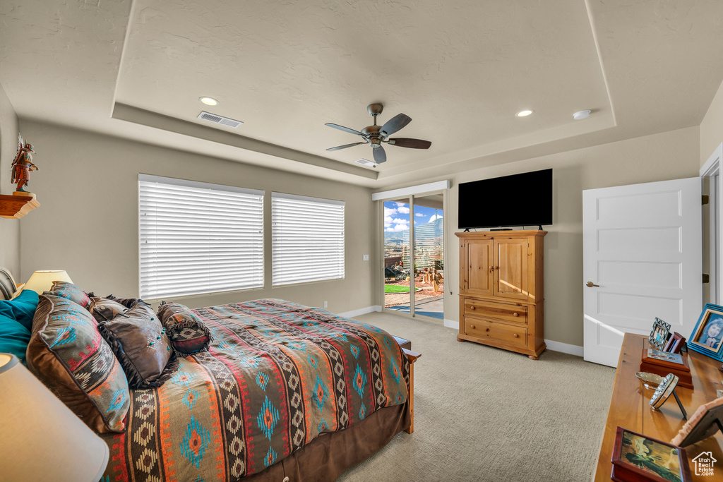 Carpeted bedroom featuring a raised ceiling, access to exterior, and ceiling fan