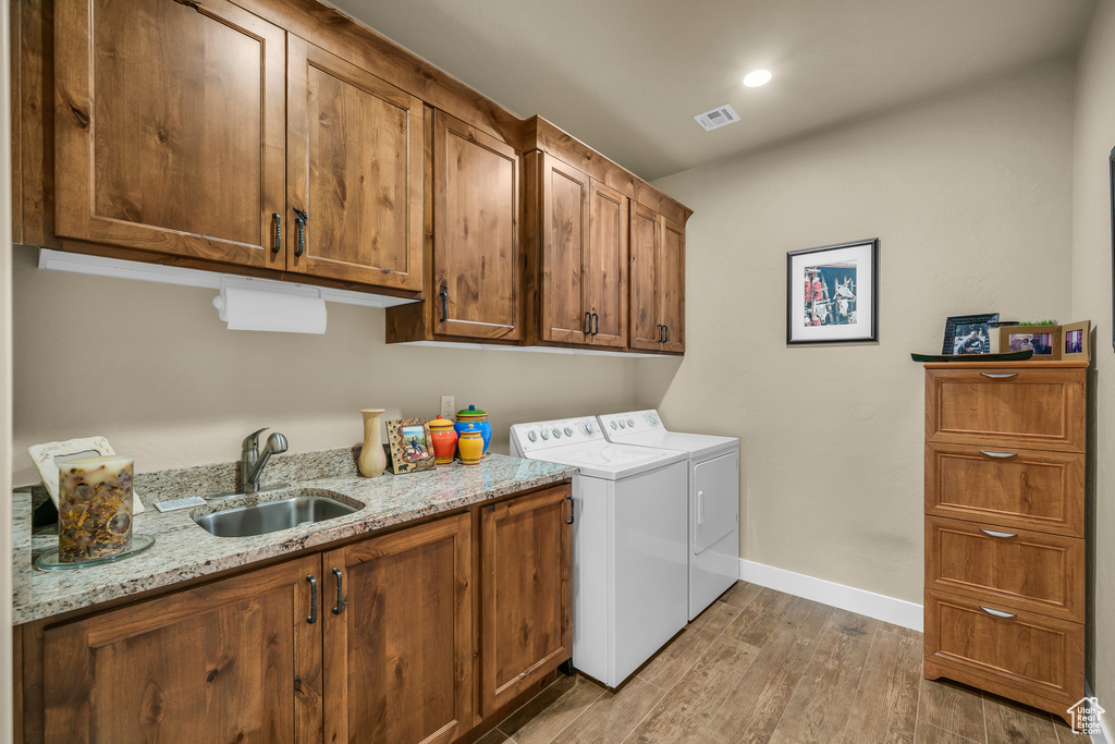 Laundry area with sink, dark hardwood / wood-style flooring, cabinets, and washing machine and dryer