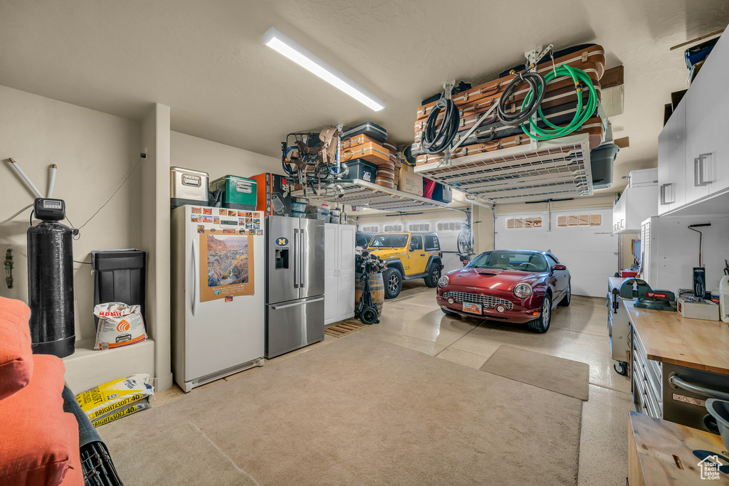 Garage with white refrigerator and stainless steel refrigerator with ice dispenser