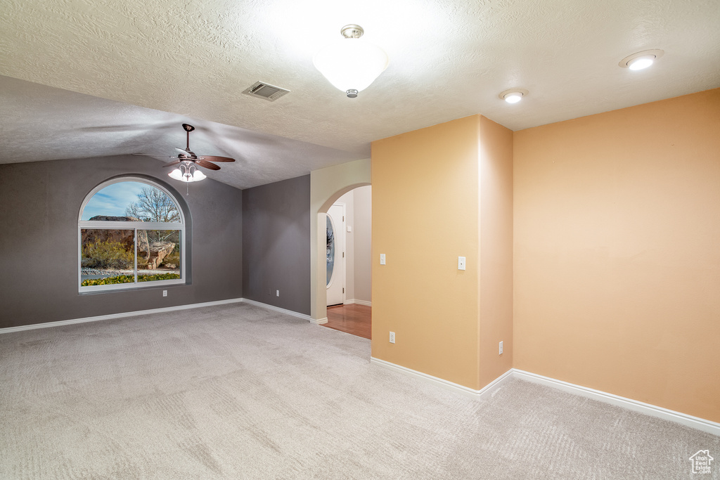 Unfurnished room featuring vaulted ceiling, light carpet, and ceiling fan
