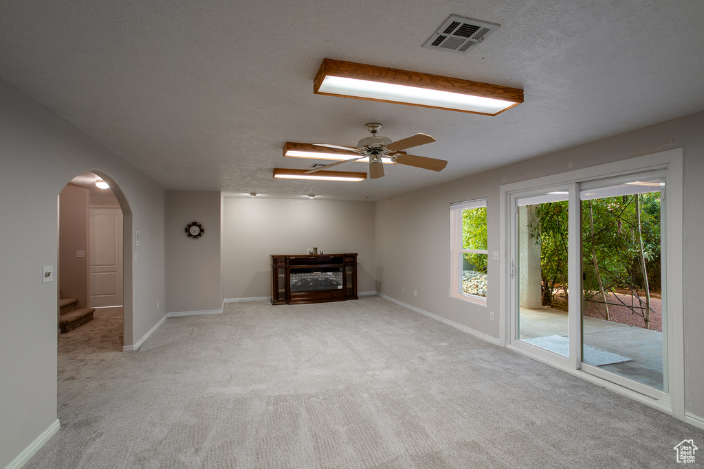 Unfurnished living room with light carpet and ceiling fan