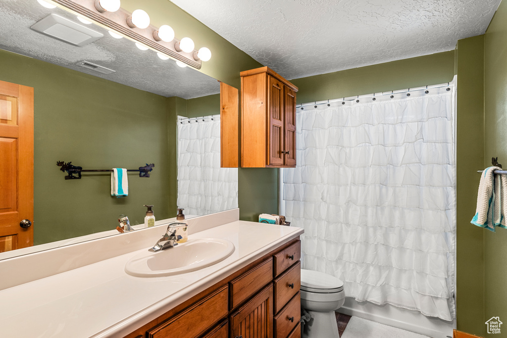 Bathroom with toilet, tile floors, a textured ceiling, and large vanity