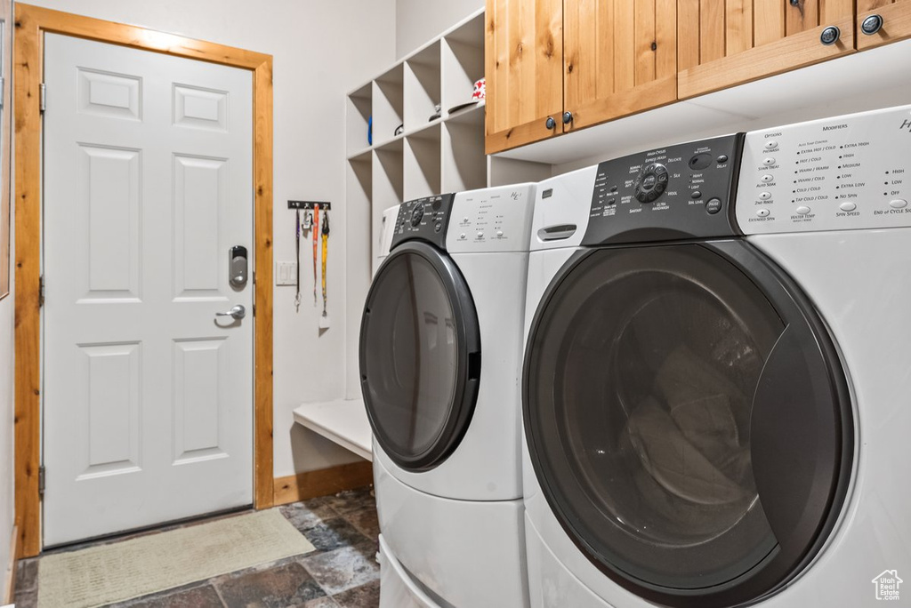 Laundry area featuring cabinets, dark tile flooring, and washing machine and dryer