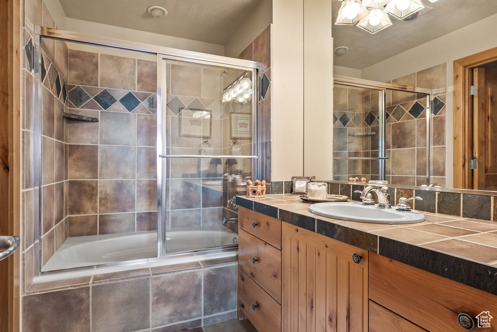 Bathroom with bath / shower combo with glass door and vanity