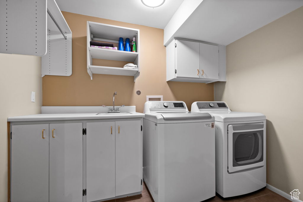 Washroom with cabinets, dark tile floors, independent washer and dryer, hookup for a washing machine, and sink