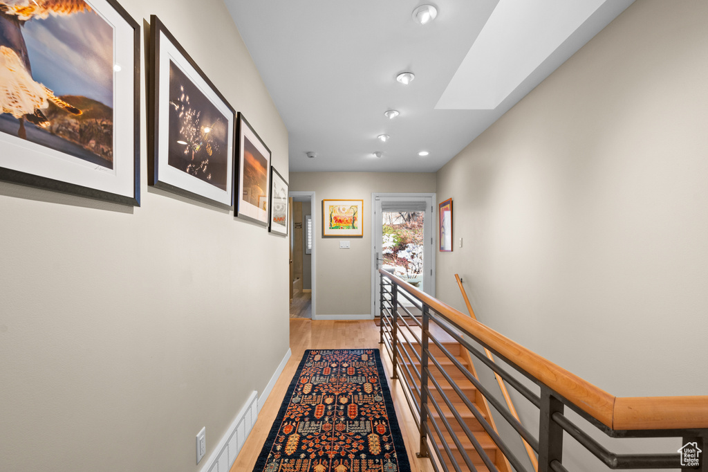 Corridor with light hardwood / wood-style flooring and a skylight