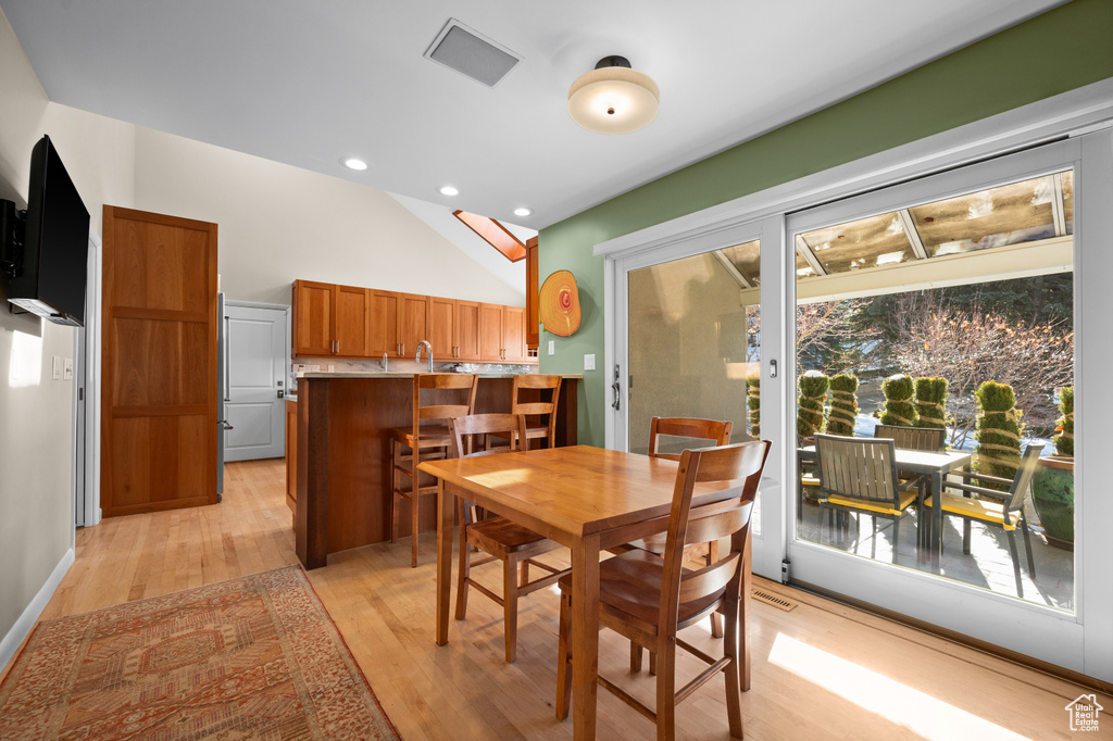 Dining area with light hardwood / wood-style flooring and lofted ceiling