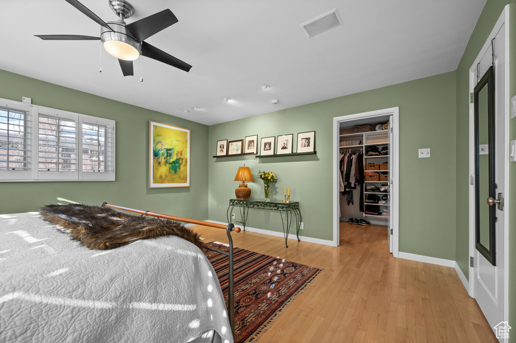 Bedroom with a closet, a walk in closet, light hardwood / wood-style flooring, and ceiling fan