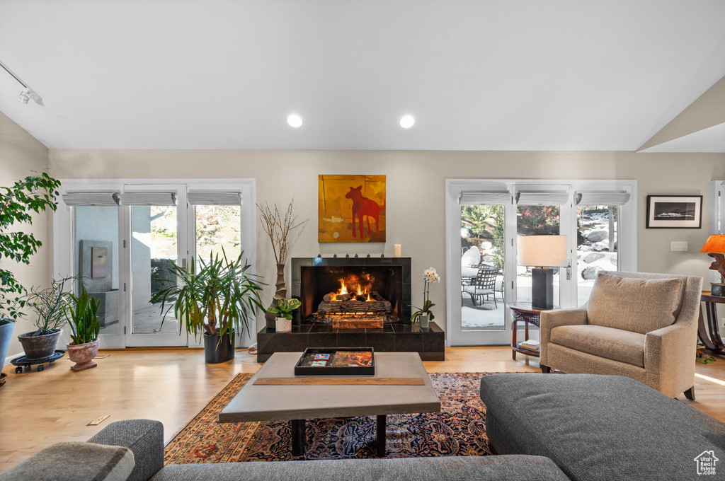 Living room featuring a tiled fireplace, vaulted ceiling, and light hardwood / wood-style flooring