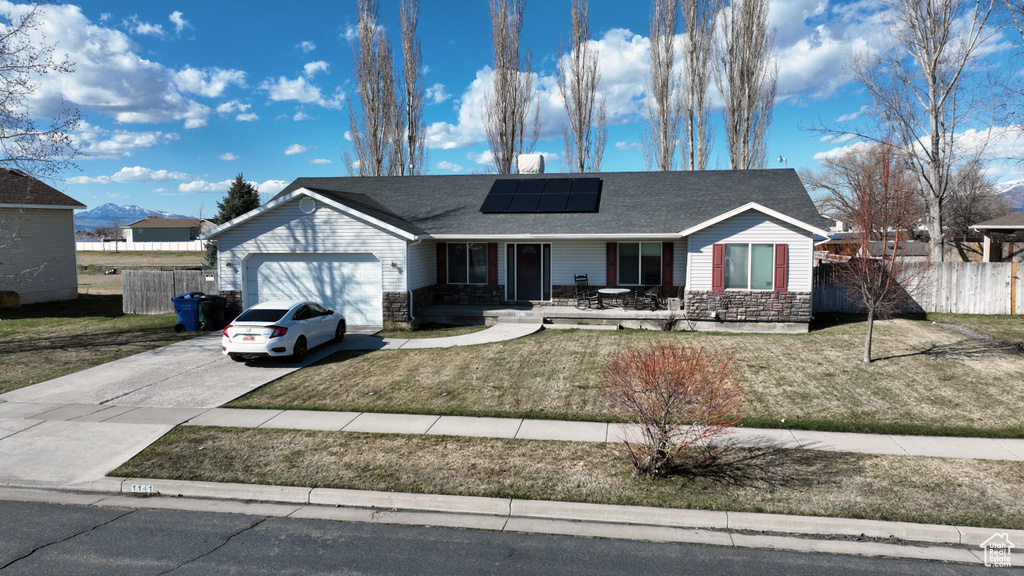 Ranch-style home with a front lawn, a garage, and solar panels