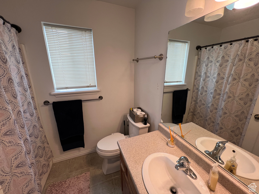 Bathroom featuring toilet, vanity, and tile flooring