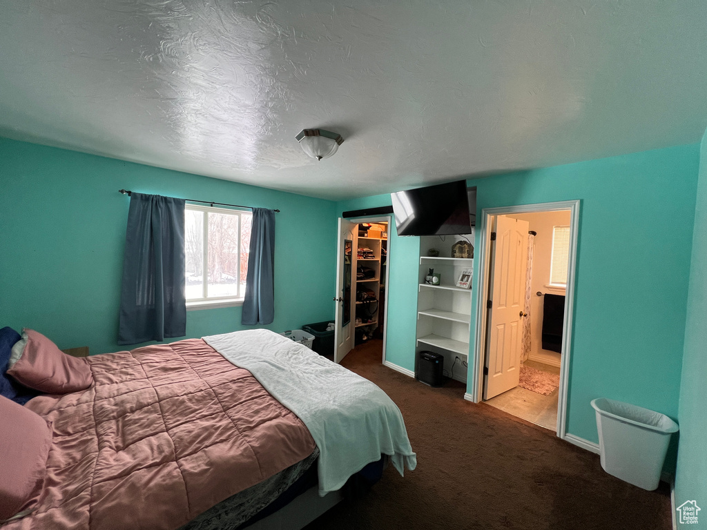 Bedroom featuring a closet, dark carpet, a walk in closet, and ensuite bath