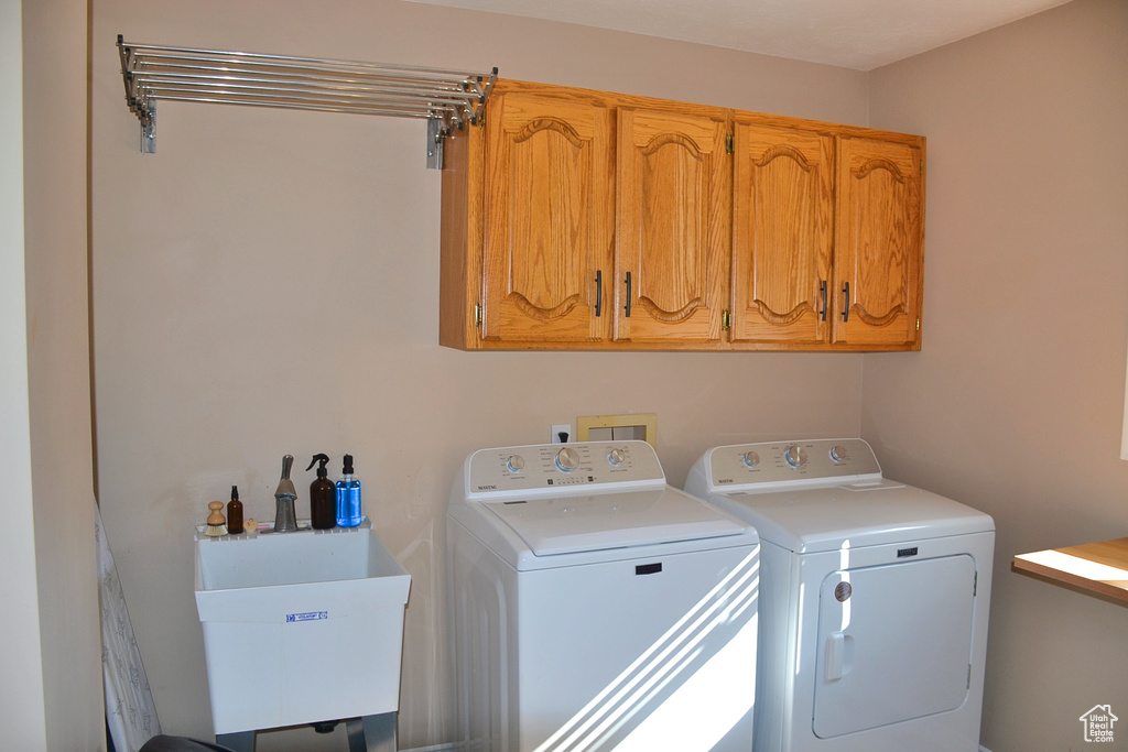 Laundry area featuring sink, cabinets, and washing machine and dryer