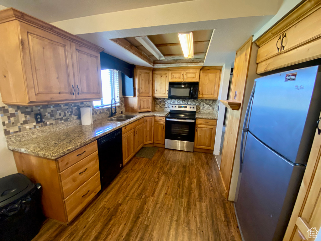 Kitchen featuring black appliances, dark hardwood / wood-style floors, sink, and backsplash