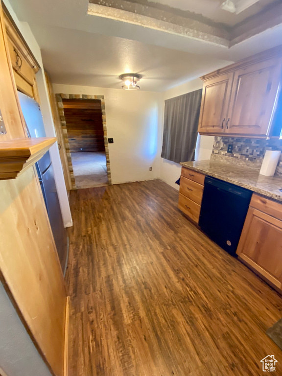 Kitchen with dark wood-type flooring, black dishwasher, light stone countertops, and backsplash