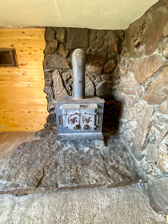 Details with wooden walls, carpet, and a wood stove