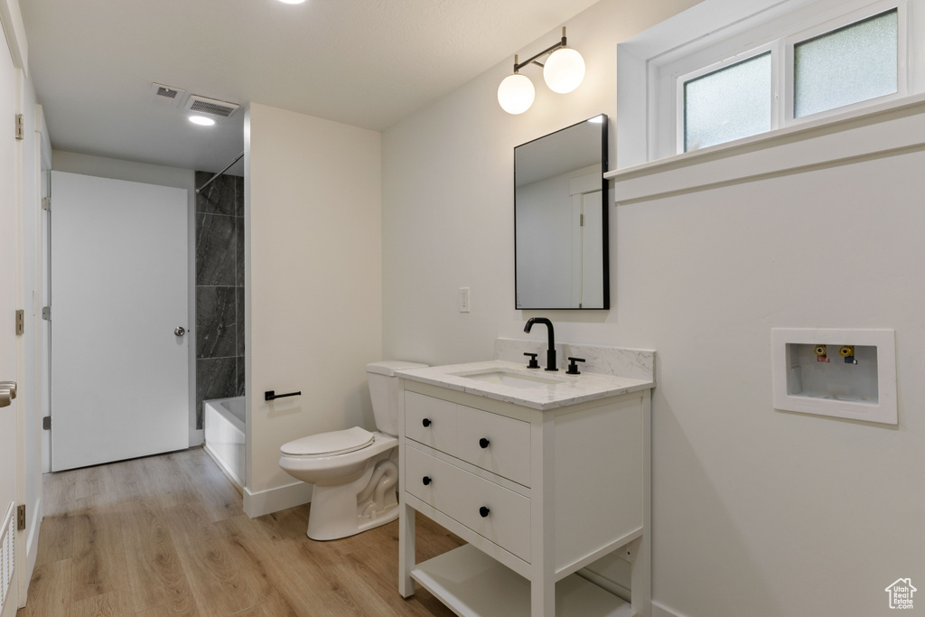Full bathroom featuring tiled shower / bath, wood-type flooring, toilet, and vanity