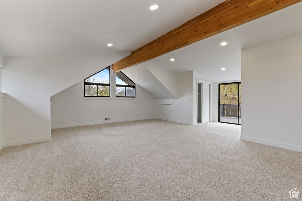 Bonus room featuring light colored carpet and vaulted ceiling with beams