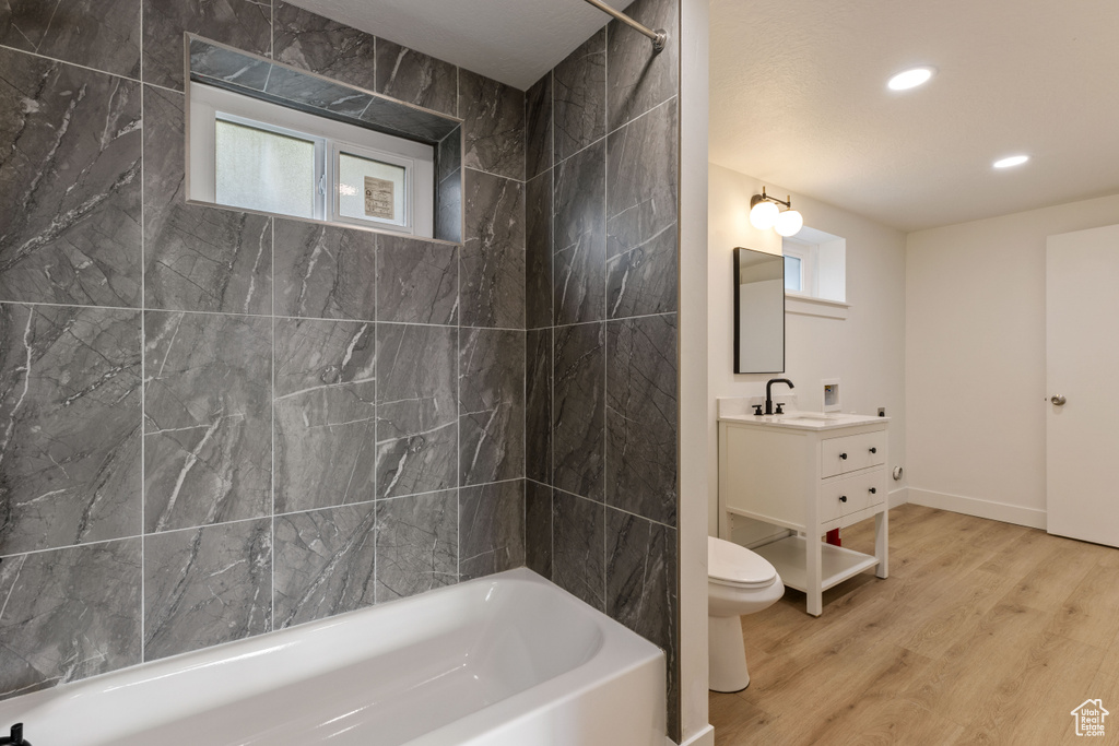 Full bathroom featuring tiled shower / bath combo, hardwood / wood-style floors, vanity, and toilet