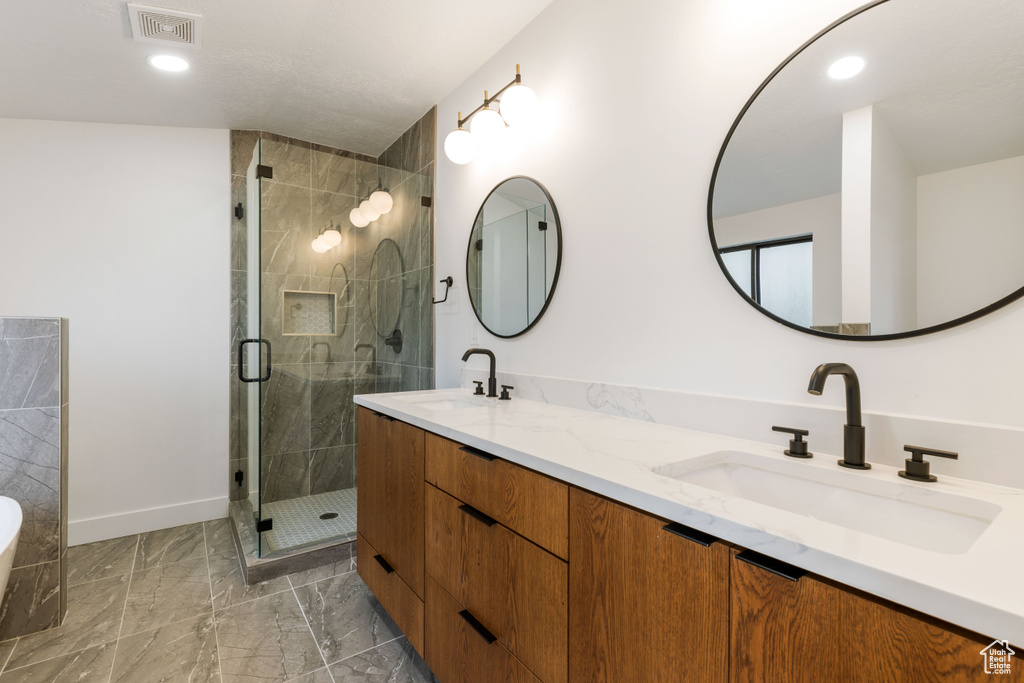 Bathroom featuring walk in shower, dual bowl vanity, and tile floors