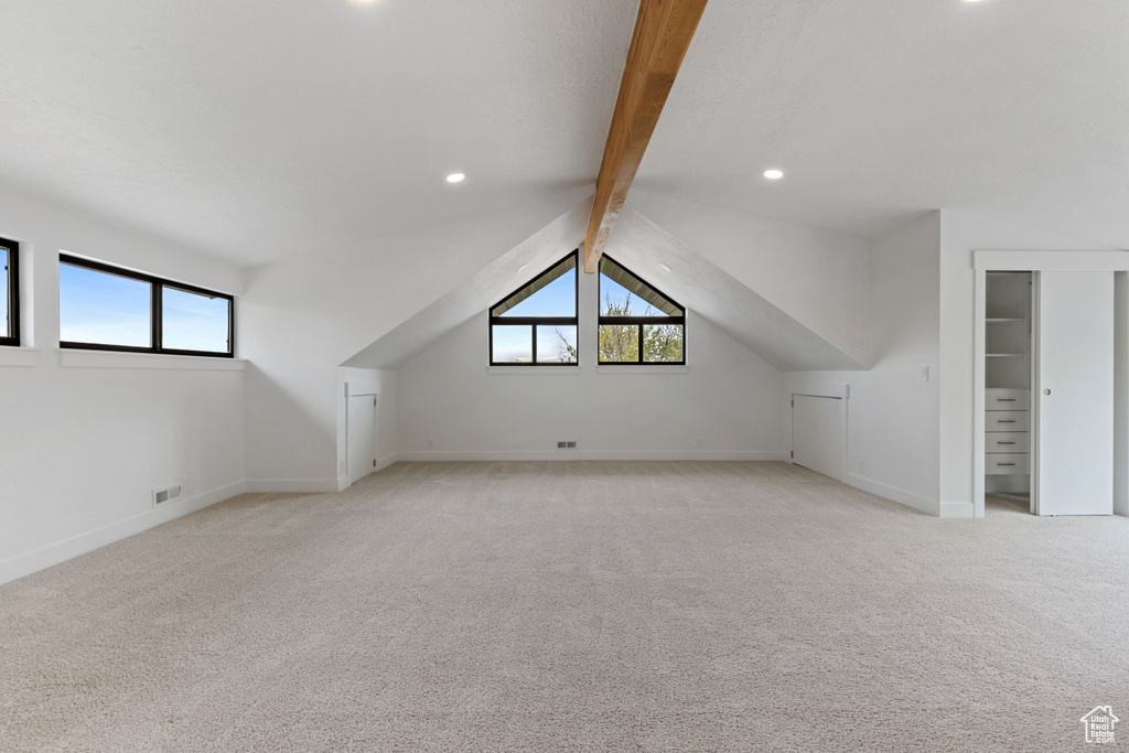 Additional living space with lofted ceiling with beams and light carpet
