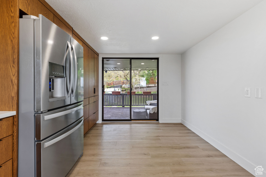 Kitchen with light hardwood / wood-style flooring and stainless steel fridge