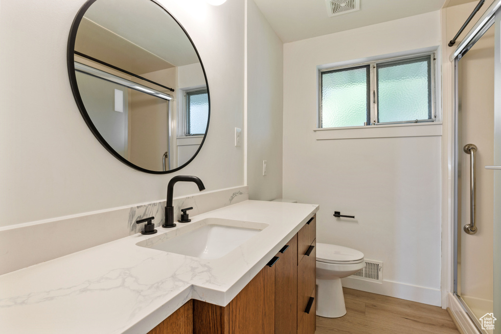 Bathroom featuring vanity with extensive cabinet space, wood-type flooring, a wealth of natural light, and toilet