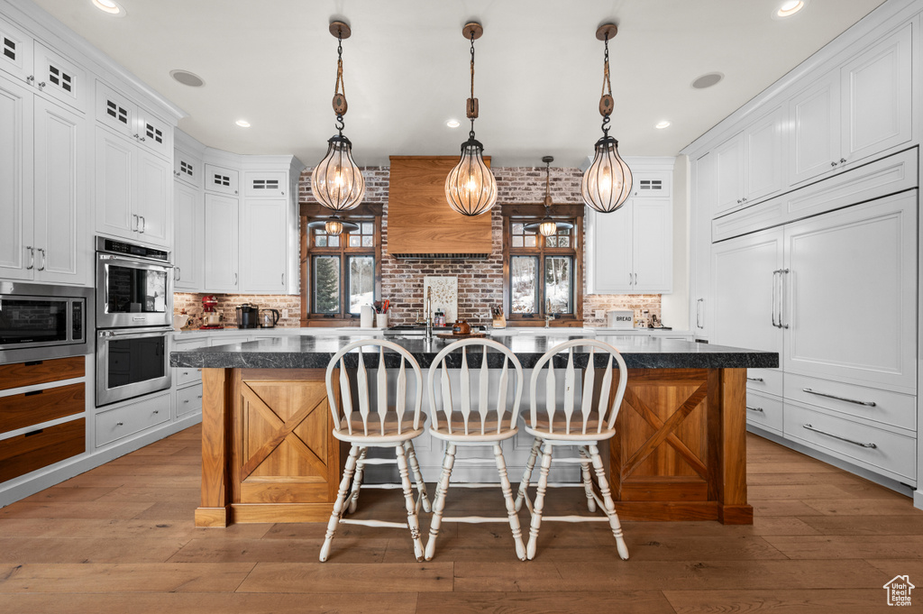 Kitchen with light hardwood / wood-style flooring, tasteful backsplash, a center island, and a breakfast bar area