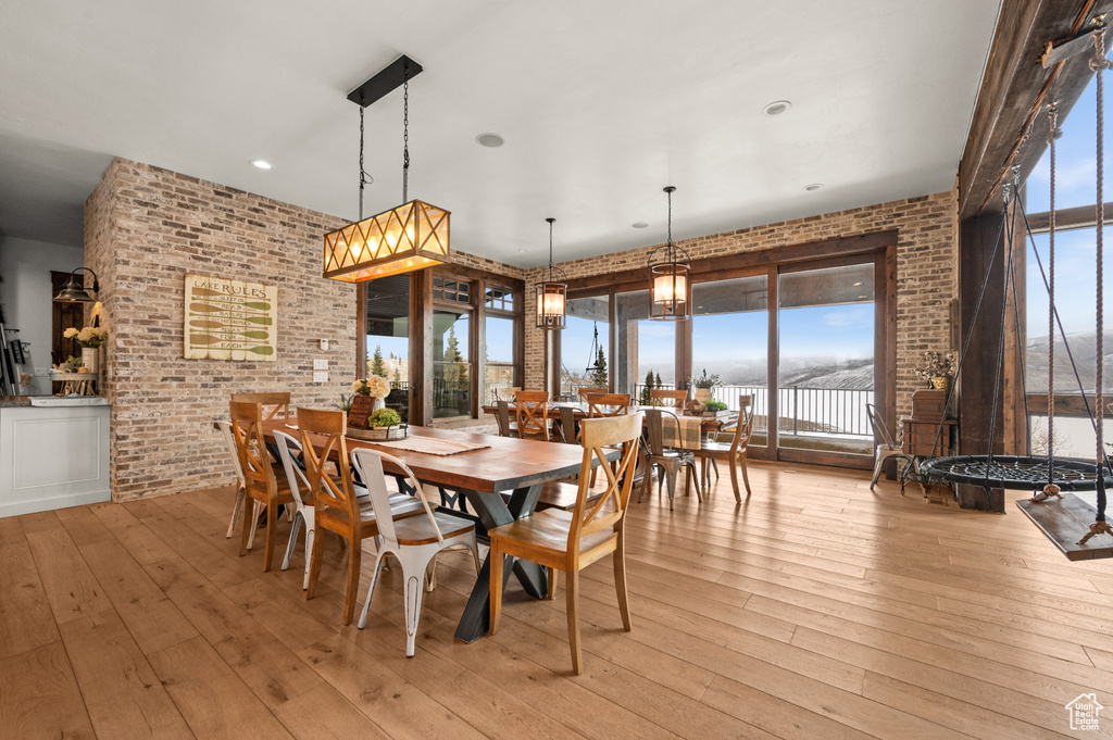 Dining space with light hardwood / wood-style floors and brick wall