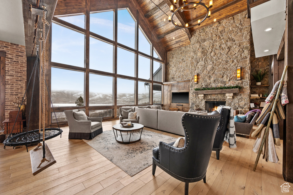 Living room featuring a stone fireplace, light hardwood / wood-style floors, an inviting chandelier, and high vaulted ceiling