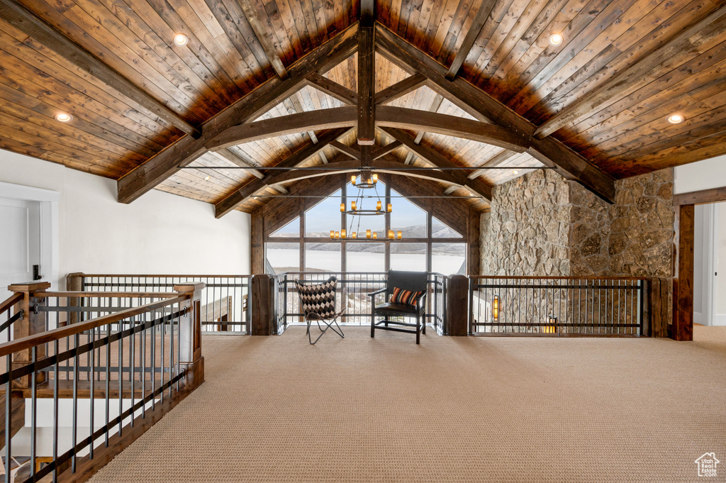 Unfurnished room featuring an inviting chandelier, dark carpet, vaulted ceiling with beams, and wooden ceiling