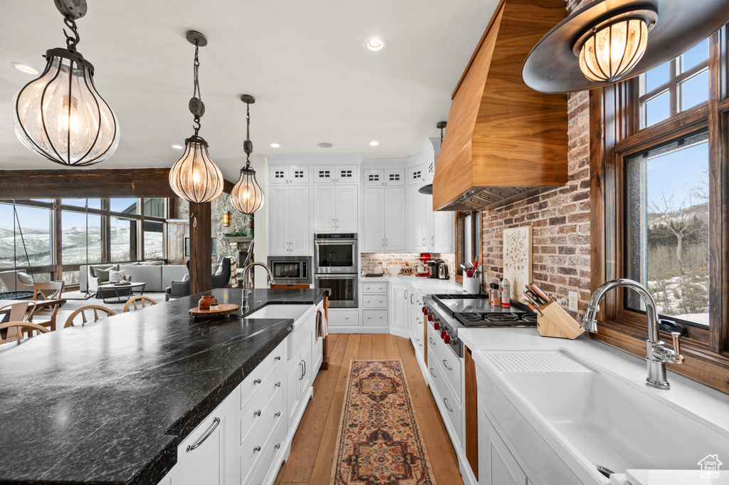Kitchen with sink, white cabinets, tasteful backsplash, and decorative light fixtures