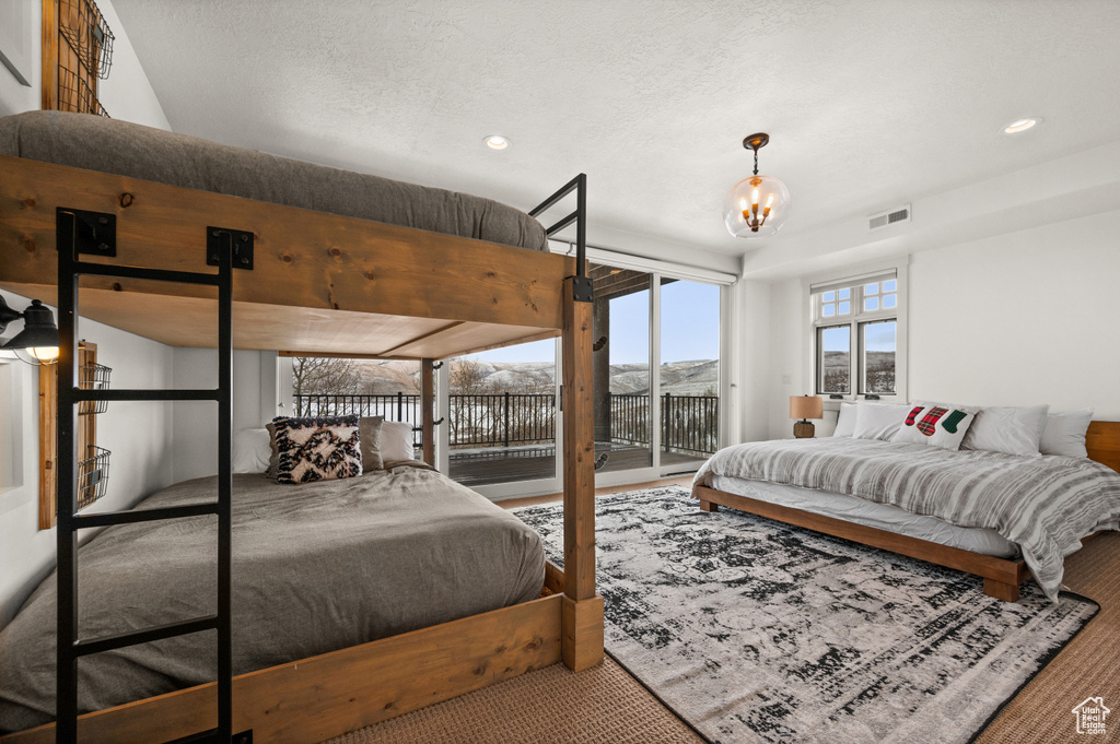 Bedroom with a textured ceiling, carpet flooring, an inviting chandelier, and access to exterior