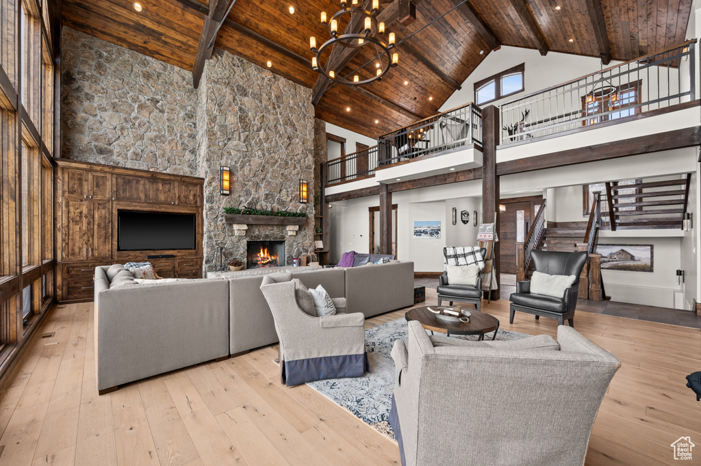 Living room featuring an inviting chandelier, wooden ceiling, a fireplace, and high vaulted ceiling