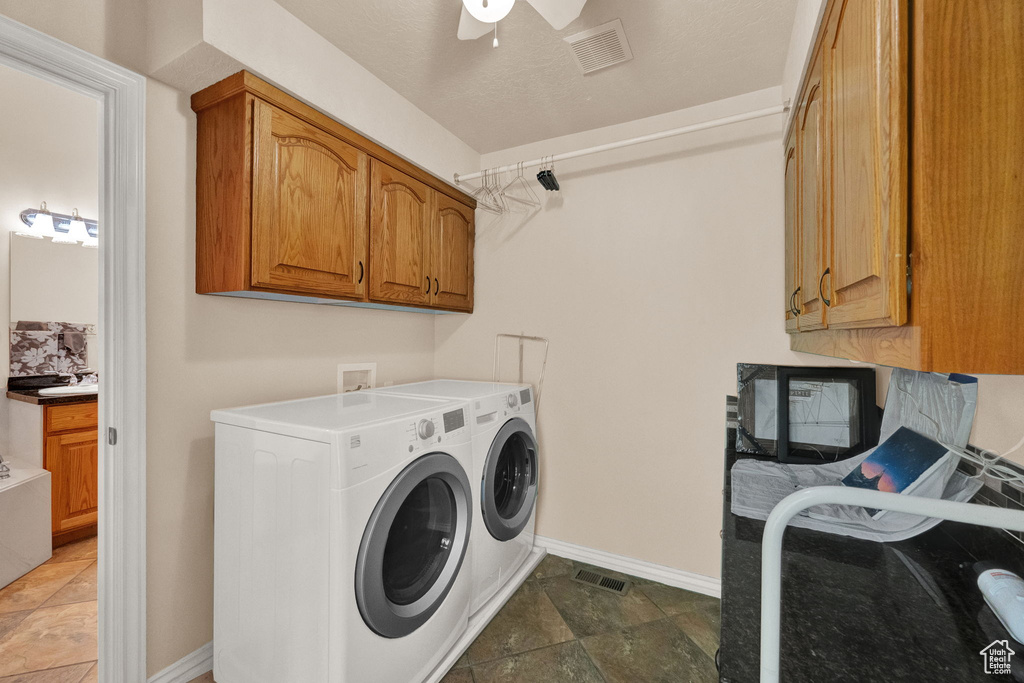 Laundry room with hookup for a washing machine, separate washer and dryer, ceiling fan, dark tile flooring, and cabinets