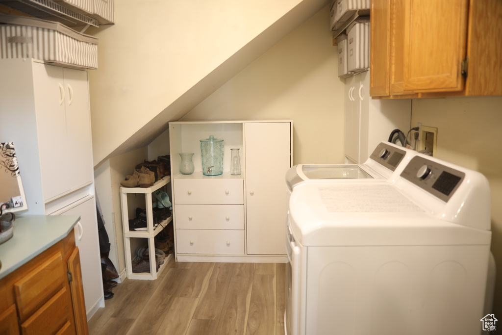 Laundry area featuring hookup for a washing machine, cabinets, light hardwood / wood-style flooring, and washing machine and dryer