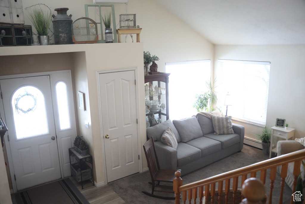 Living room featuring baseboard heating, dark hardwood / wood-style floors, and vaulted ceiling